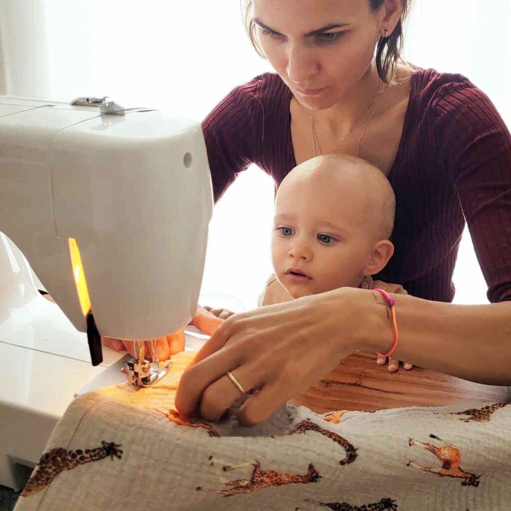 žena šije a na kolenách jej sedí dieťa